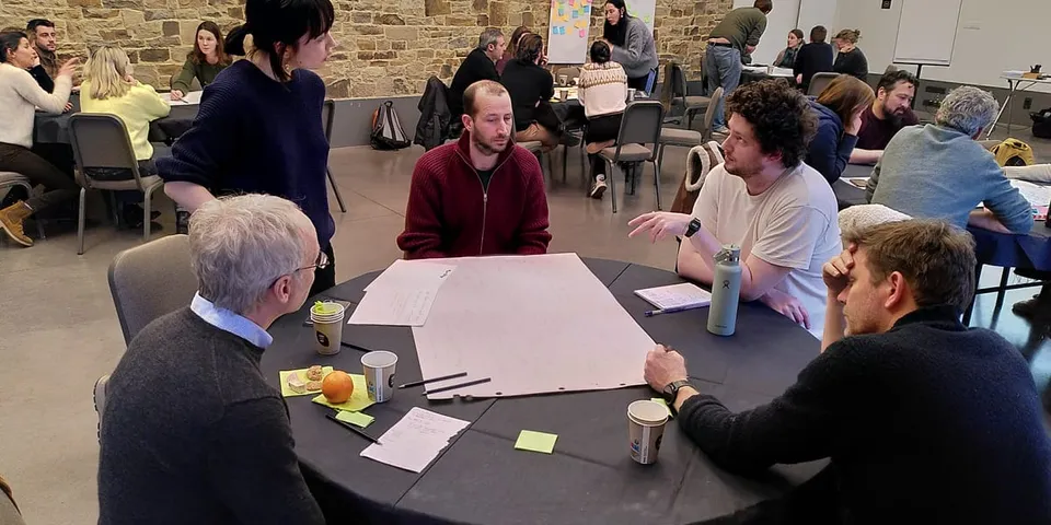 Collega’s in een workshop rond een tafel vol notities, tijdens de teamretraite van 2026.